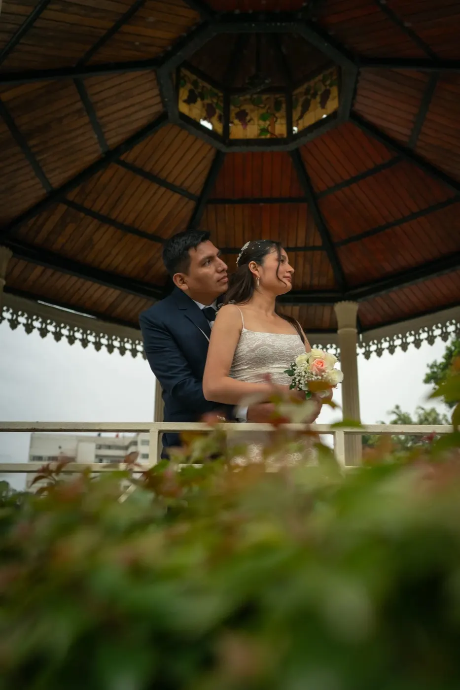 Mabel y Julio abrazados bajo una glorieta de madera el día de su boda